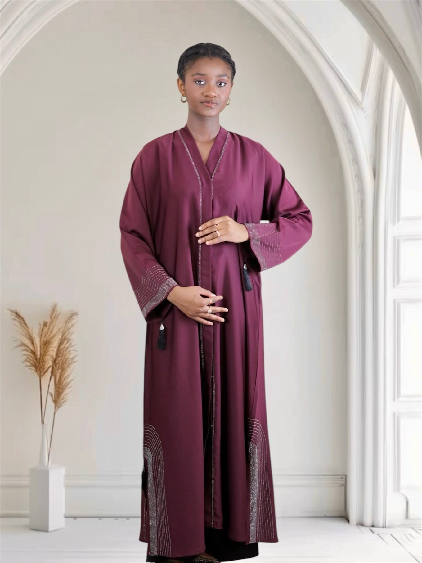 Woman wearing a long, dark purple dress embellished with rhinestone