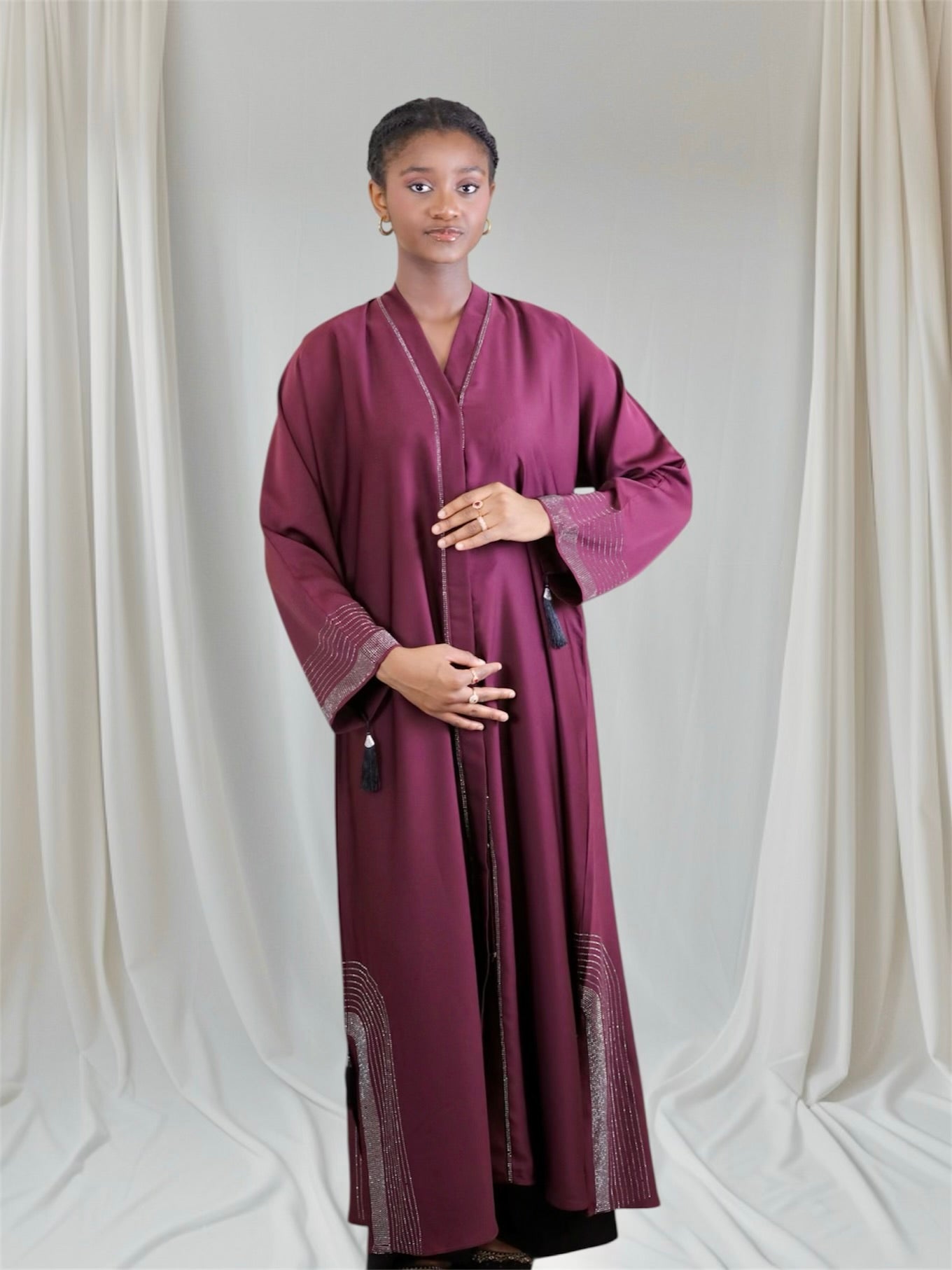Woman wearing a long, burgundy abaya with embellished with rhinestone
