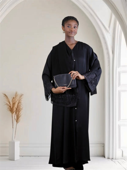 Woman holding a black handbag in a minimalistic indoor setting