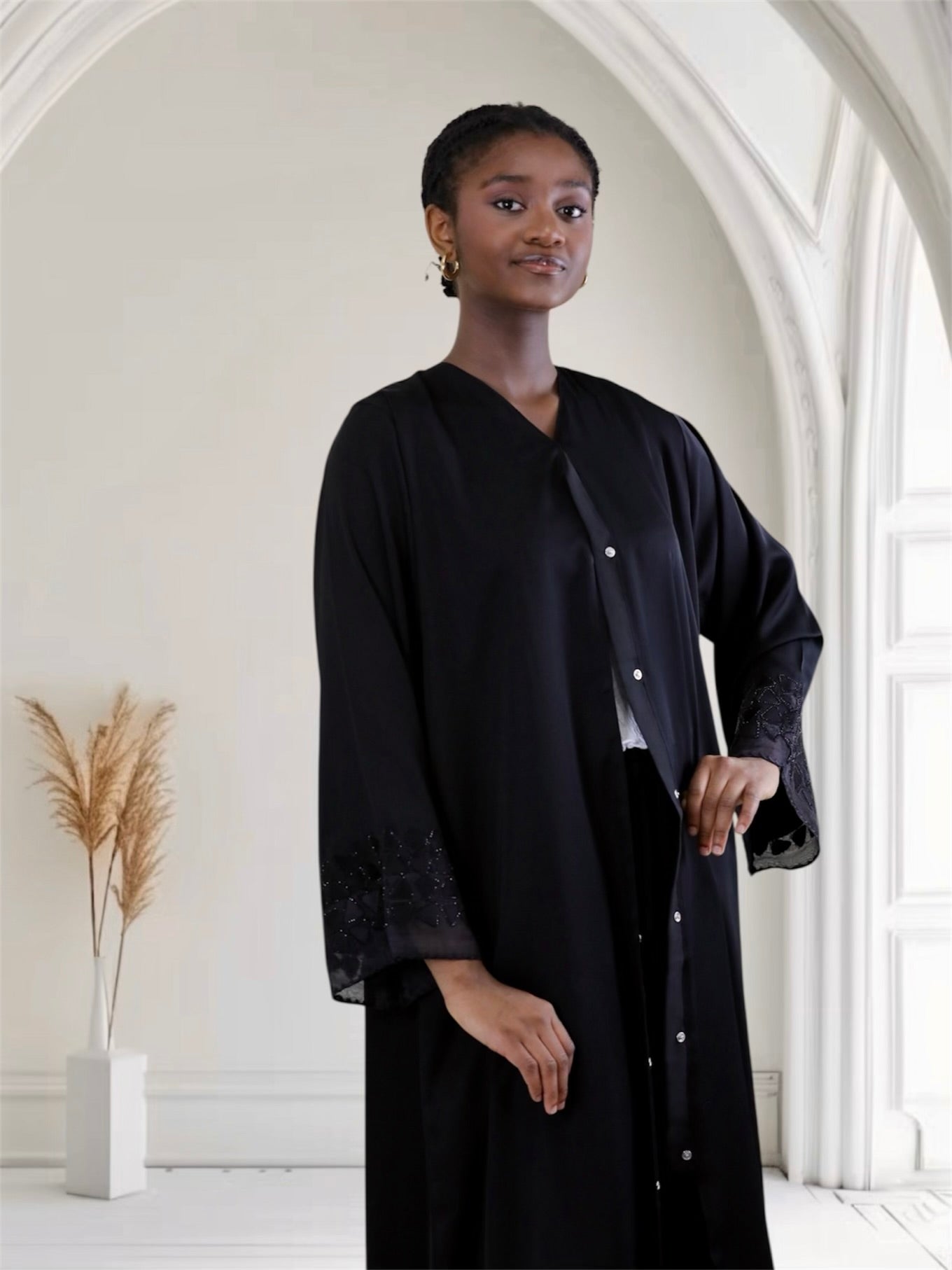 Woman wearing a black outfit in a bright, minimalistic room.