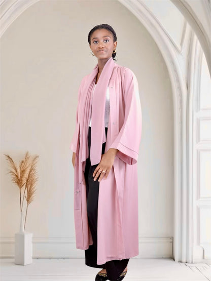 Woman wearing a pink long dress in a minimalistic room.