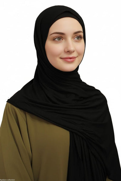 Woman wearing a black hijab and green outfit on a white background