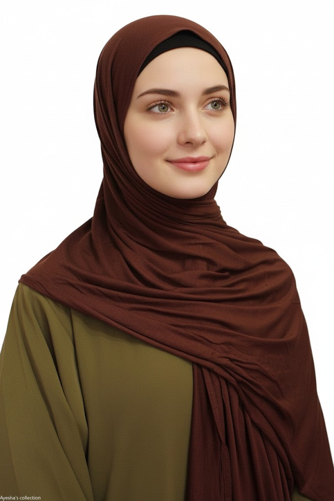 Woman wearing a brown hijab and green top on a white background