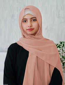 A woman wearing a light peach chiffon scarf