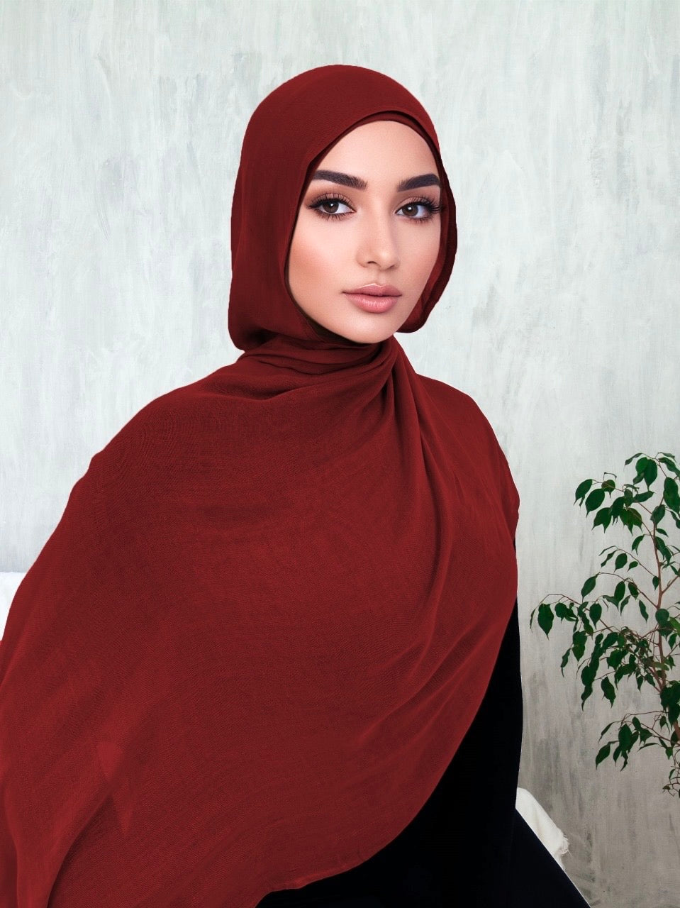 A woman wearing a burgundy modal hijab, draped over the head and shoulders.
