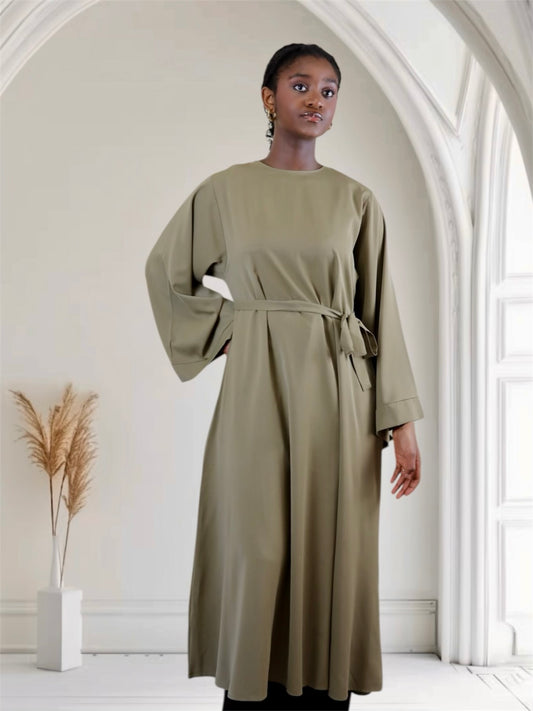 Woman wearing a long sage green dress with belt