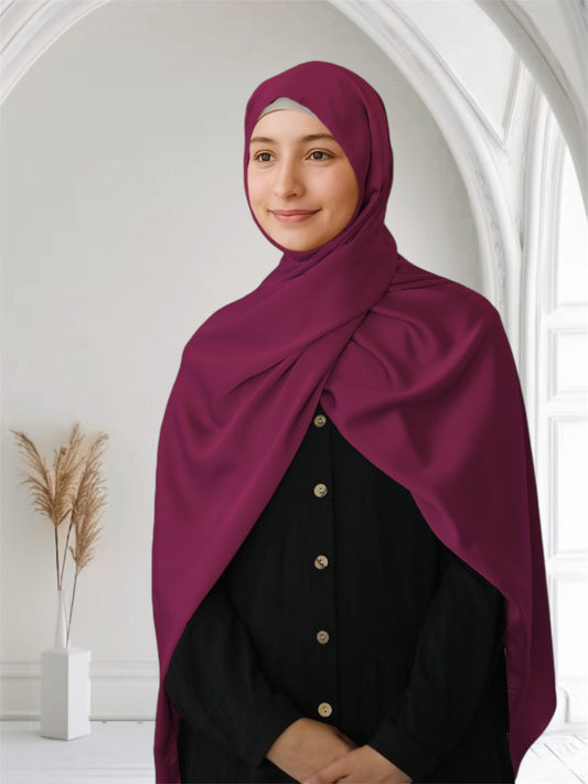 A woman wearing a maroon matte satin silk scarf draped over her head and neck, matching with her outfit.