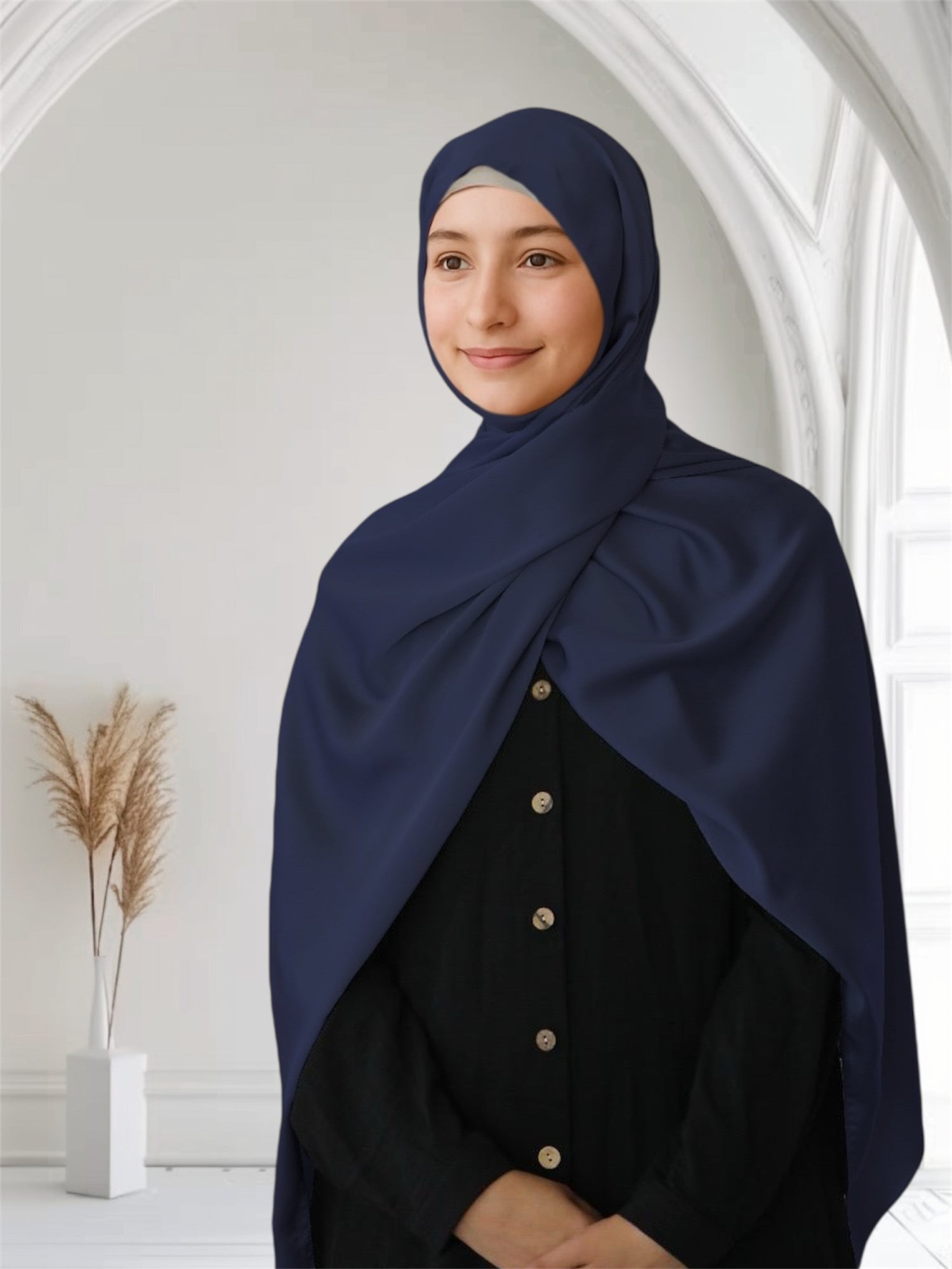 A woman wearing a navy blue satin silk scarf draped over her head and shoulder