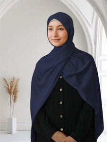 A woman wearing a navy blue satin silk scarf draped over her head and shoulder