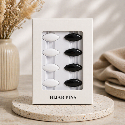 Packaged hijab pins with black and white colors on a neutral background